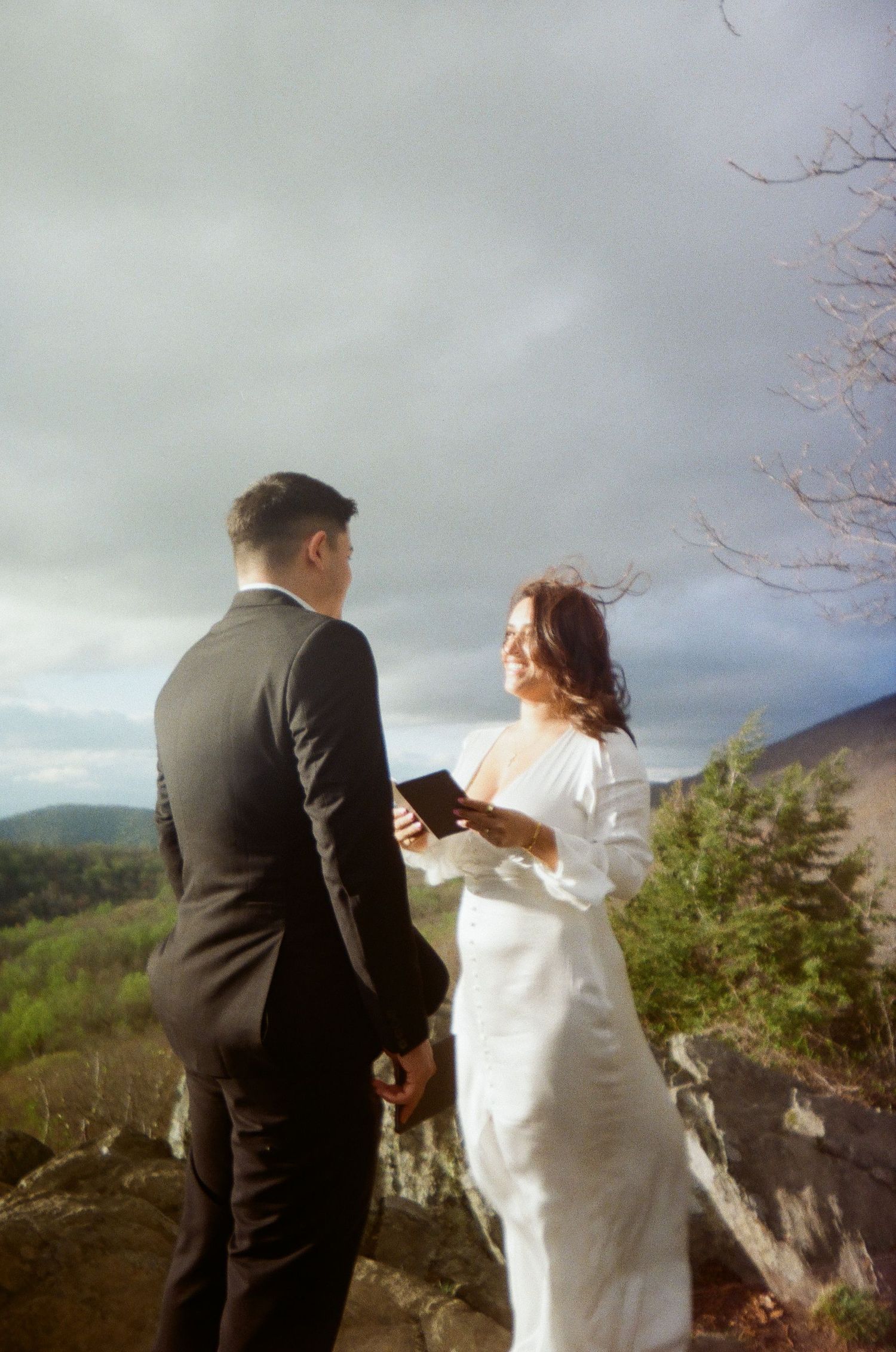 A couple sharing a special moment during their mountain elopement ceremony against a cloudy dramatic sky.