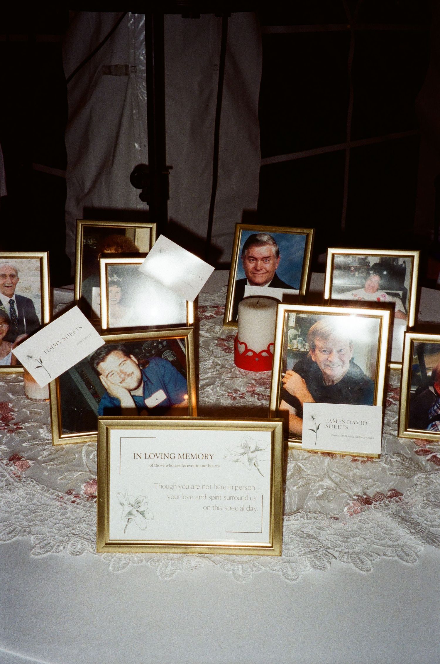 Framed photographs and a certificate displayed on a white lace tablecloth at a formal event.