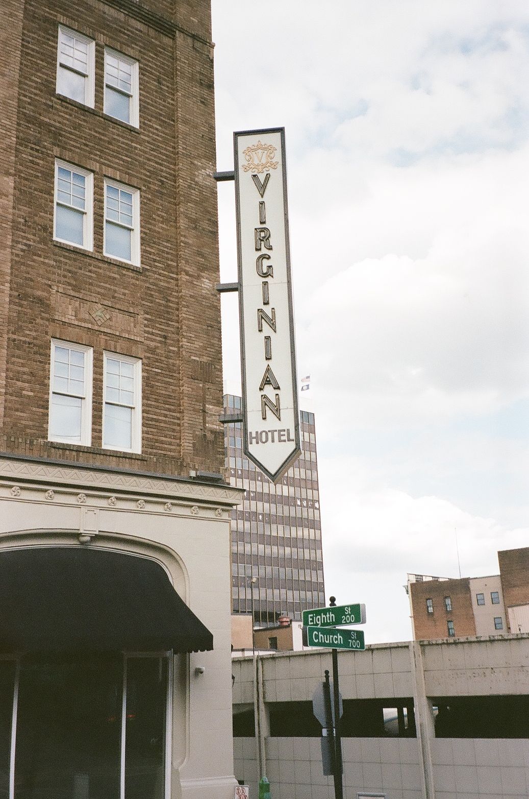 Vintage Virginian Hotel sign mounted on a brown brick building facade with an arrow pointing downward.