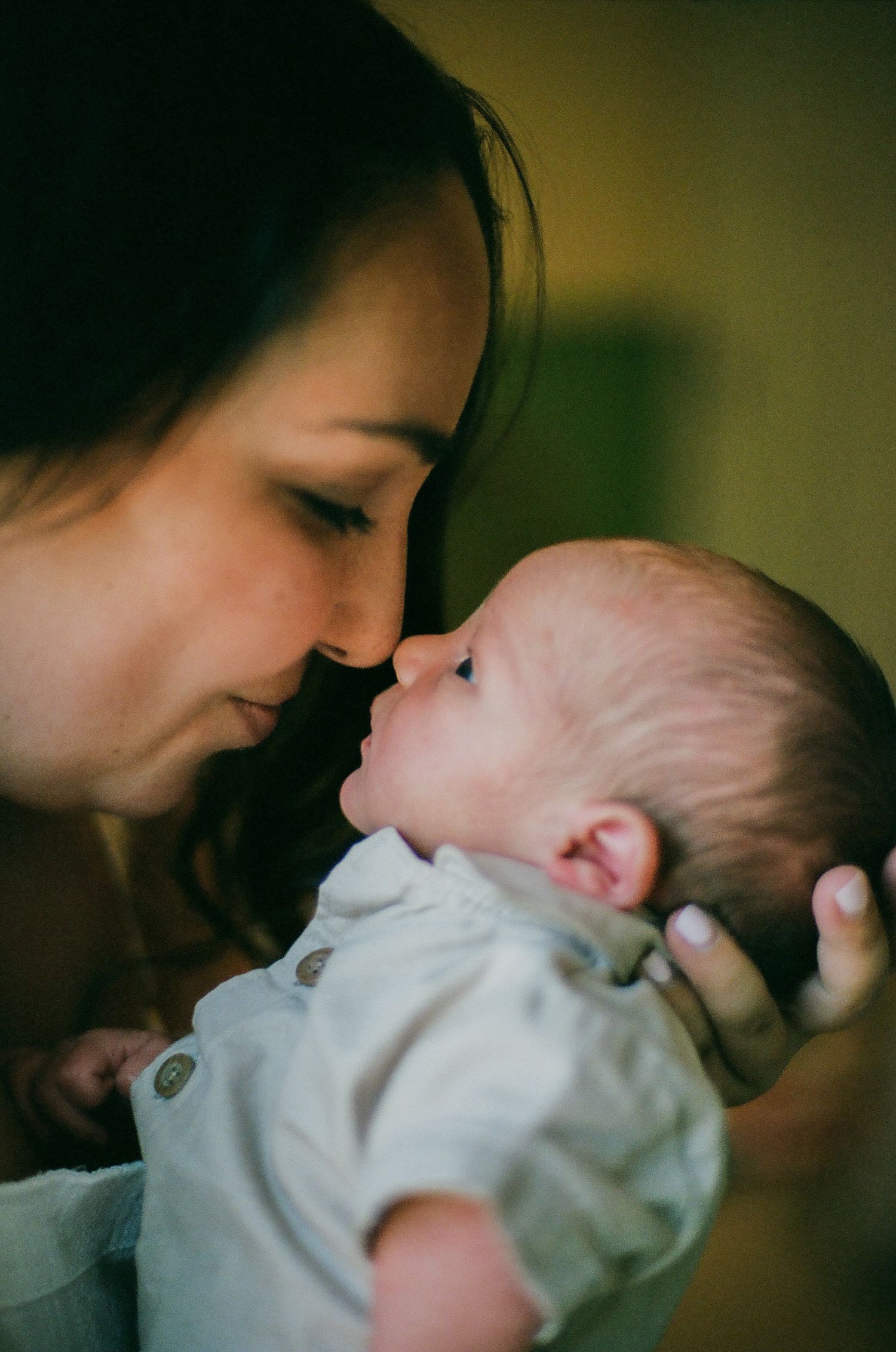 A tender moment between a mother and her newborn baby touching noses, sharing an intimate bond.