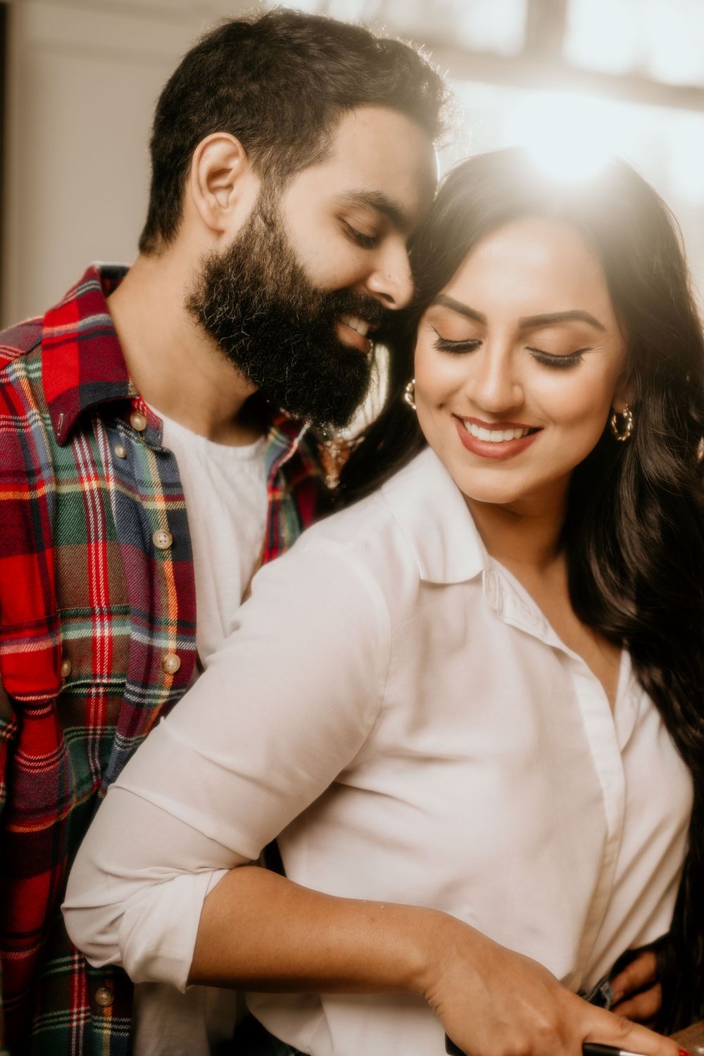A romantic couple sharing an intimate moment in soft lighting while dressed in casual attire.
