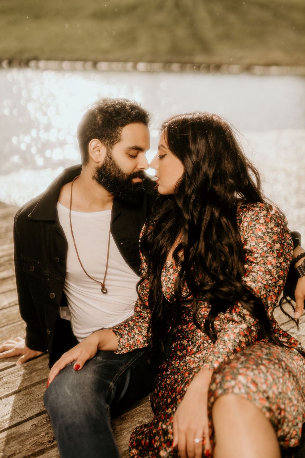 Romantic couple in an intimate moment on wooden deck with woman wearing sparkly dress and man in casual black jacket.