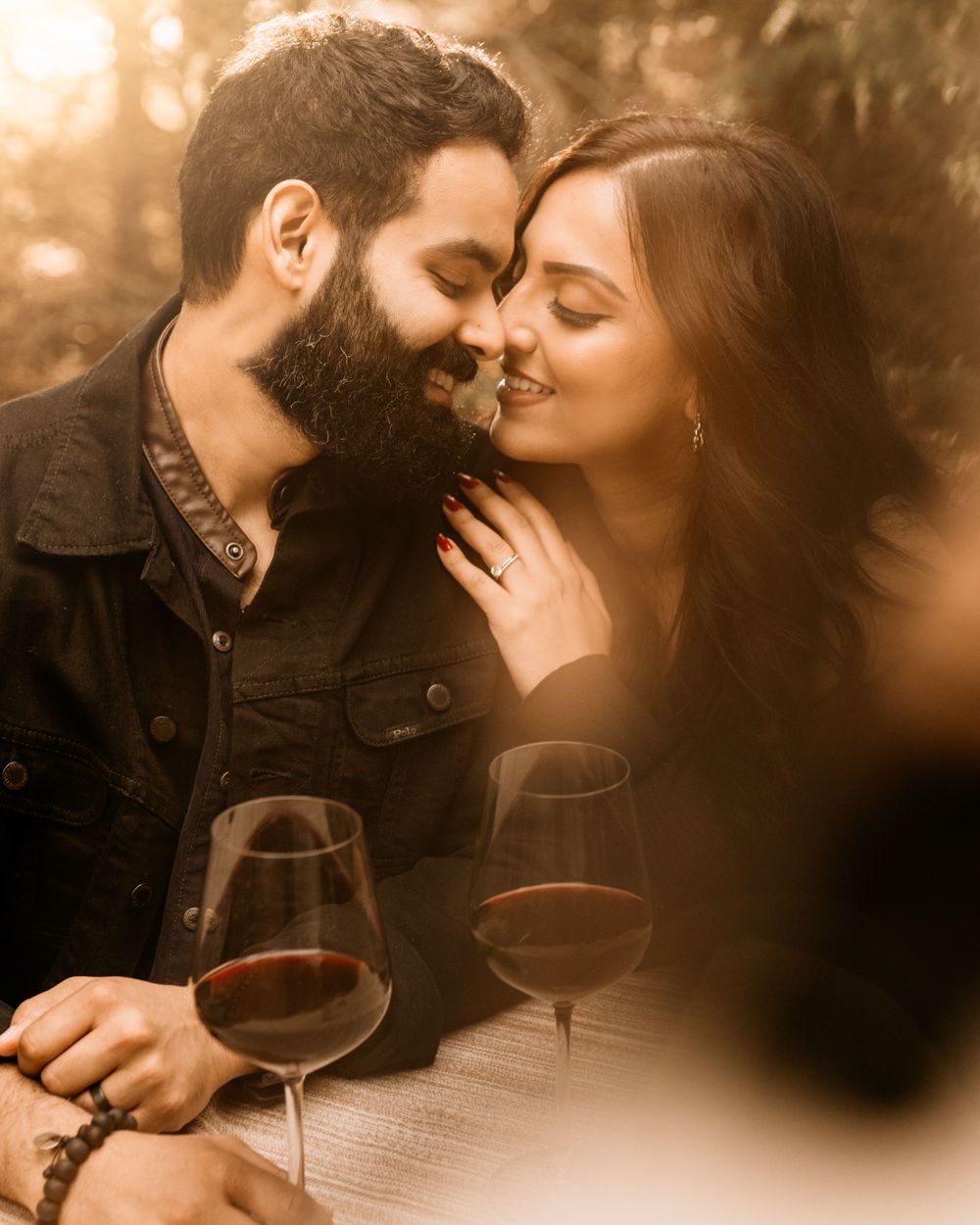 An intimate moment between a couple with wine glasses on a warm-toned outdoor date.