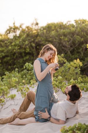 Couple relaxing on beach blanket during golden hour photoshoot.
