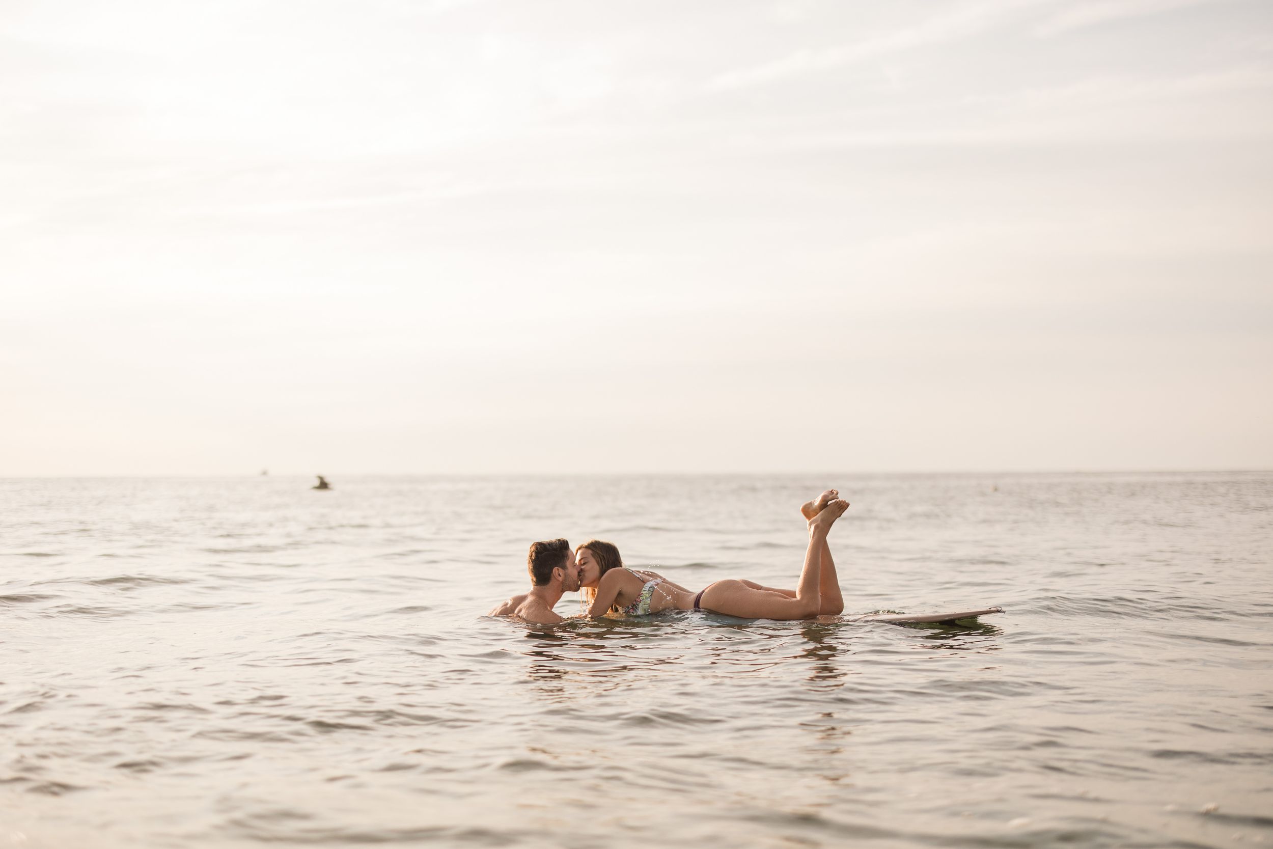 Playful couple floating together in calm ocean waters at sunset.
