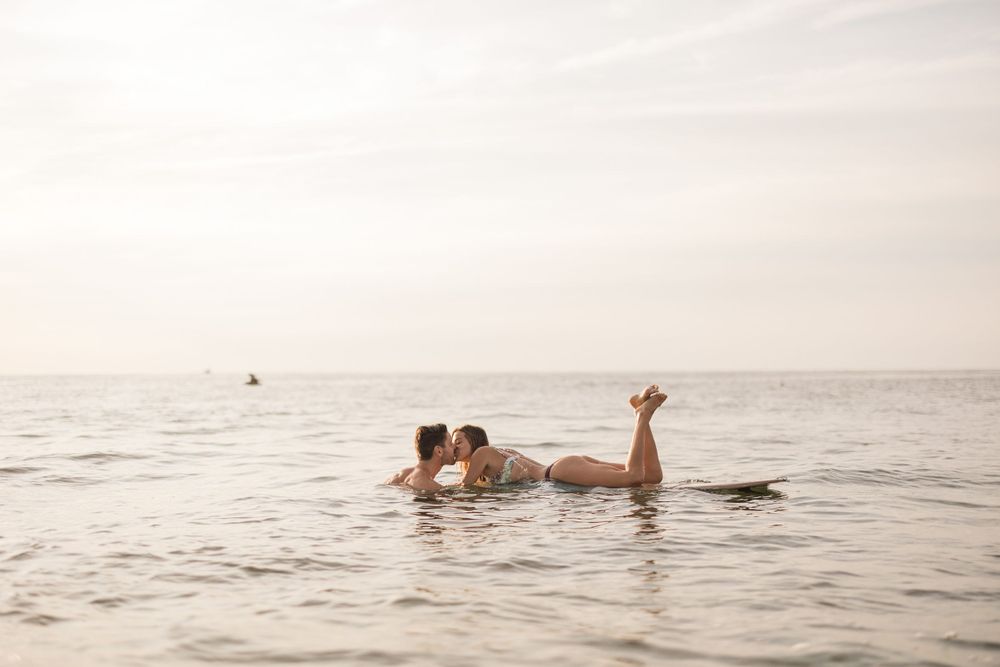 Playful couple floating together in calm ocean waters at sunset.