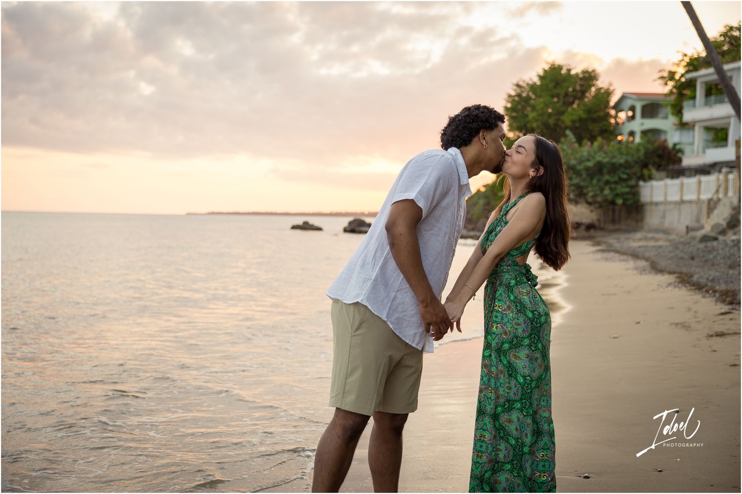 A romantic sunset beach scene shows a couple in a white shirt and green dress embracing by the ocean.