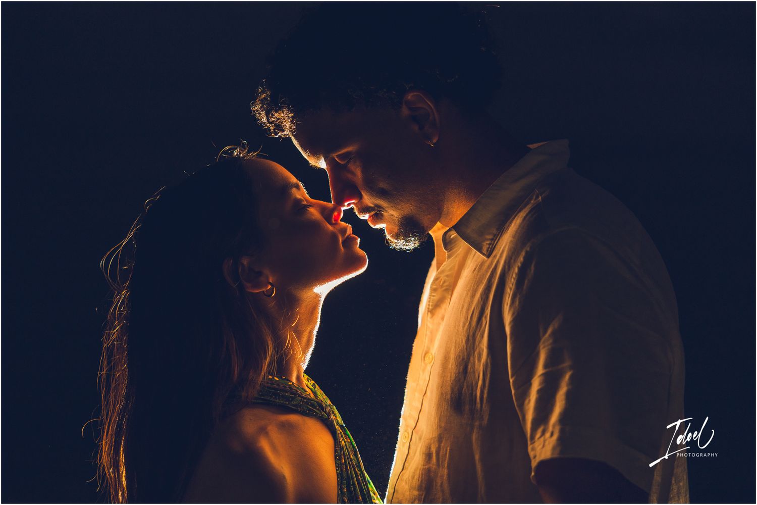 Artistic backlit silhouette photo of a romantic couple in warm glowing light.