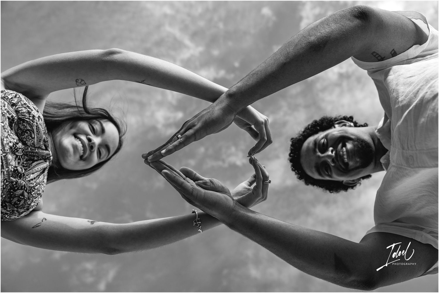 Artistic black and white underwater photograph of two swimmers creating symmetrical mirror poses beneath the surface.