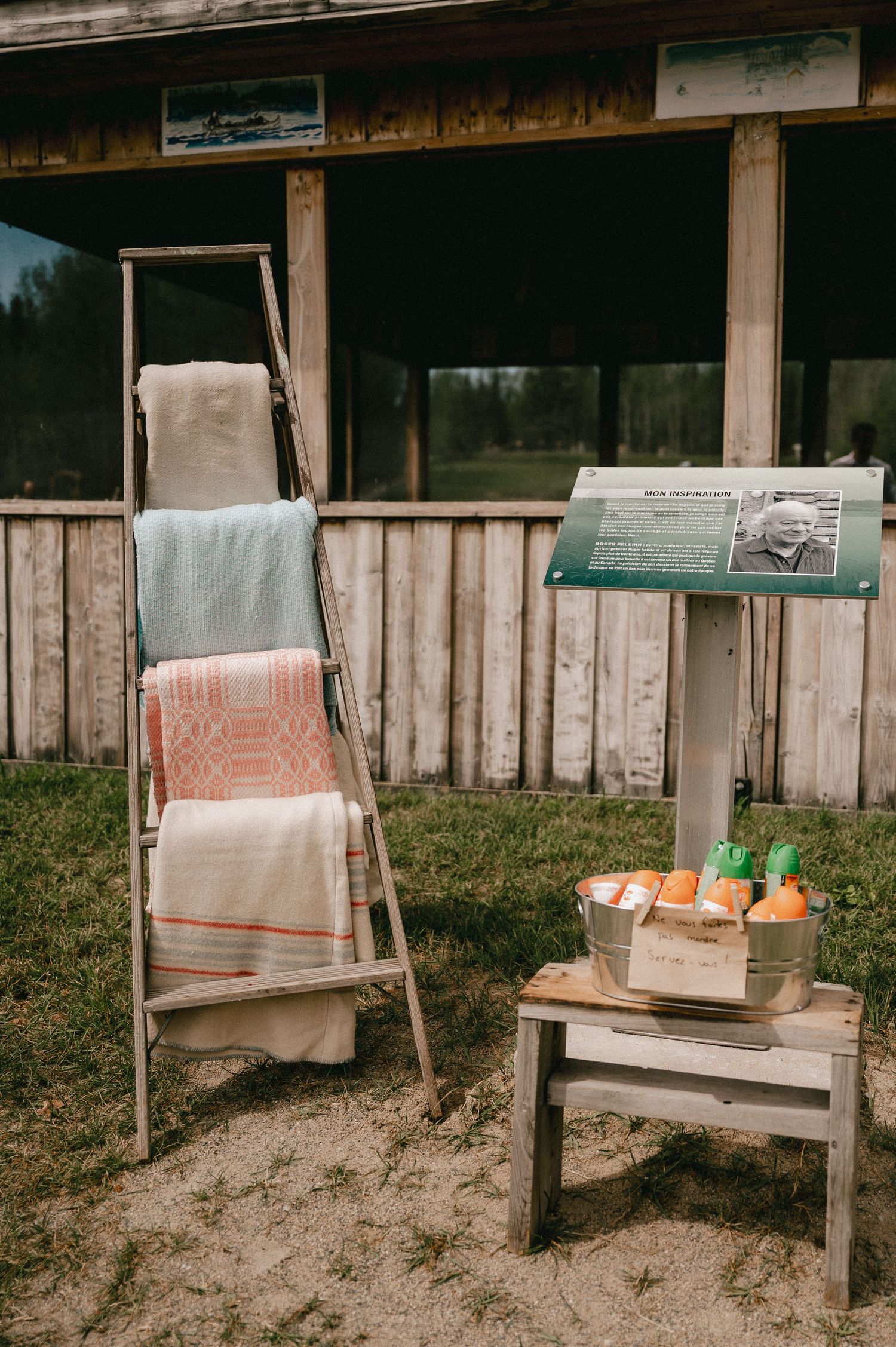 Pastel colored towels hanging on ladder with refreshment station set up on wooden bench.
