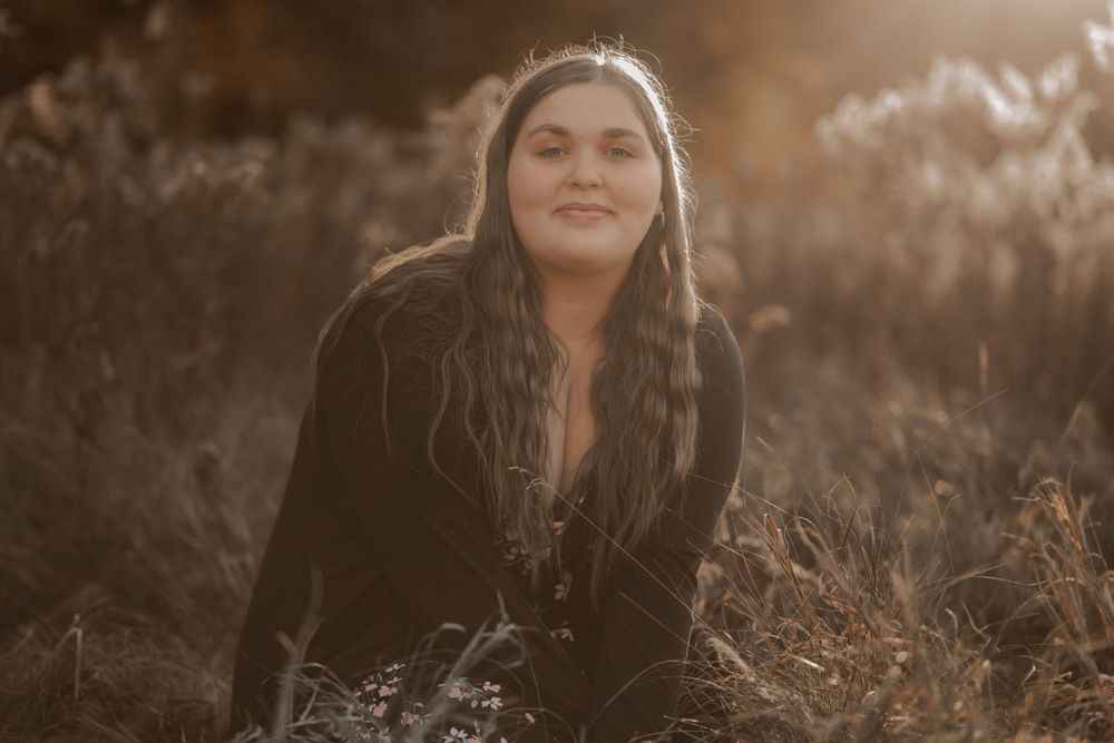 Warm sunlit portrait in tall grass during golden hour with soft backlighting.