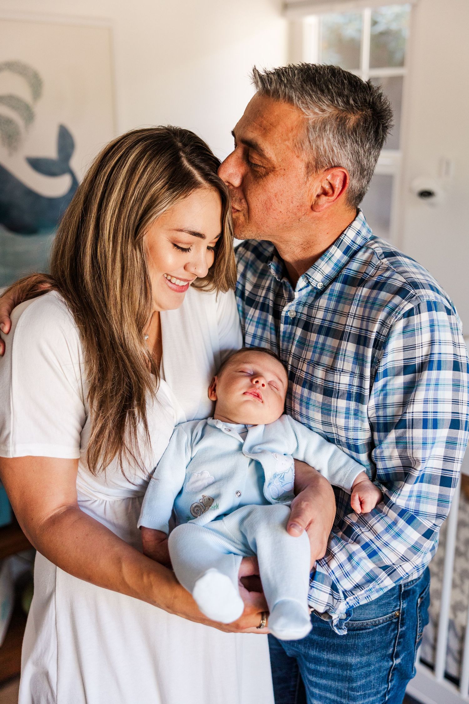Tender family moment with a newborn baby in a bright nursery room.