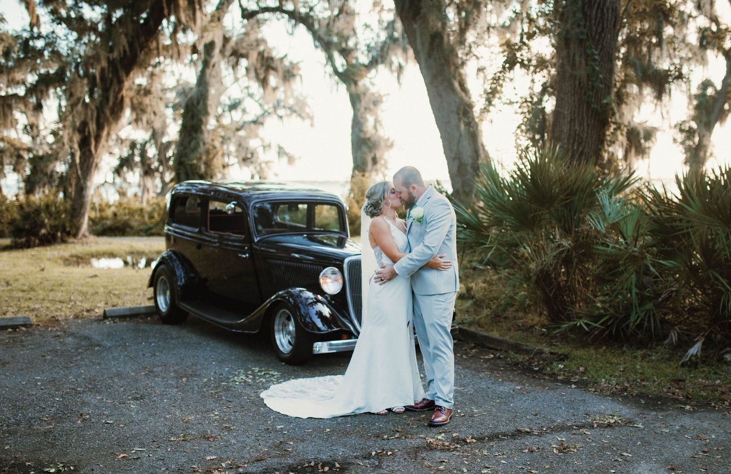 Vintage car provides classic backdrop for wedding couple's portrait.