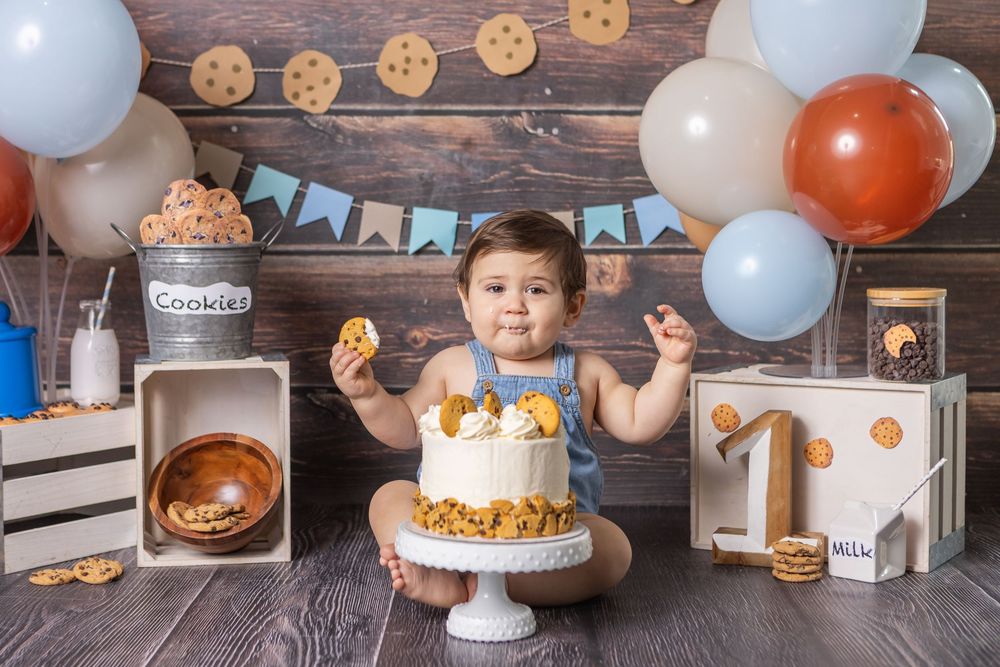 Baby's first birthday cake smash with cookies and cream theme, balloons, and wooden crate decorations.