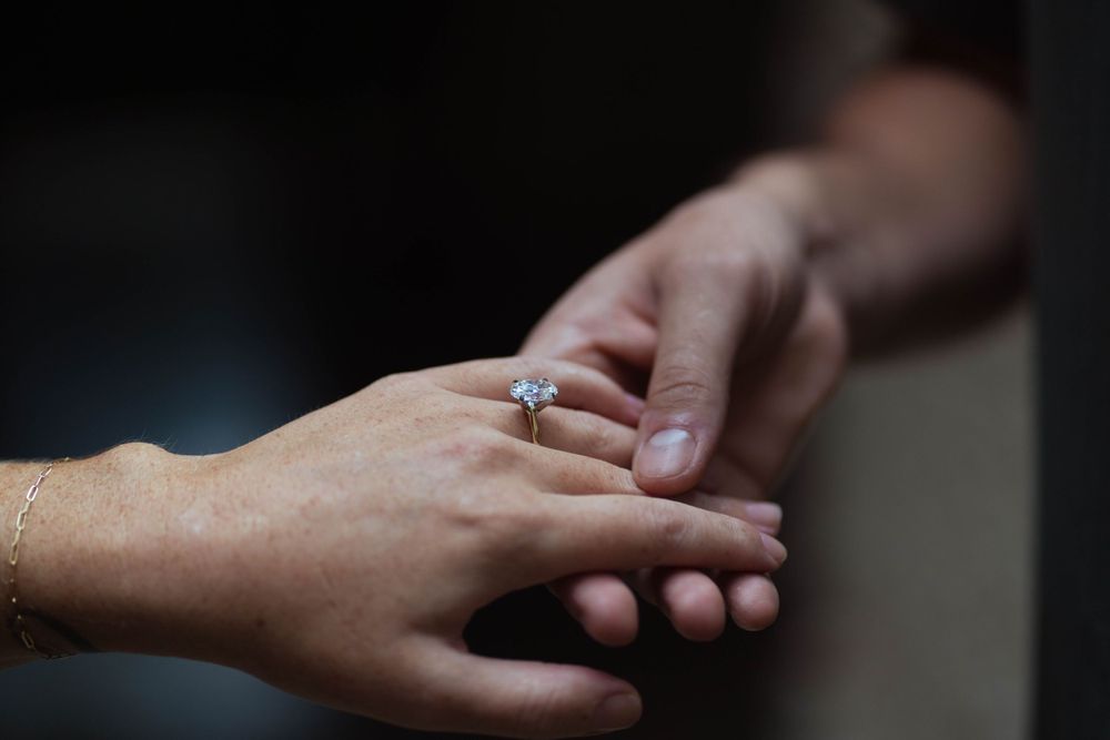 Close-up of a sparkling oval engagement ring on a bride’s hand. Romantic proposal photography with elegant wedding jewelry details.
