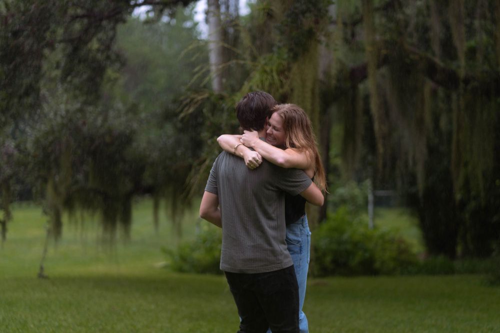 Emotional embrace in a lush, rainy forest. Romantic engagement photography capturing love and connection in nature.
