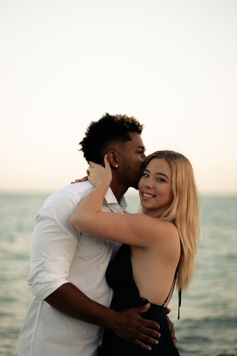 Romantic beach engagement session at sunset. Couple shares a sweet moment by the ocean, capturing love and natural connection.