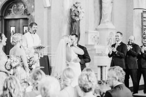 A wedding ceremony taking place in an ornate church with guests watching from wooden pews.