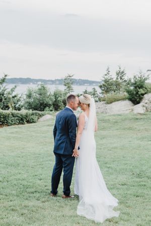 Wedding couple sharing intimate moment on hilltop overlooking coastal waters.