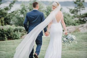 Wedding couple walking hand in hand with flowing veil in gentle breeze.