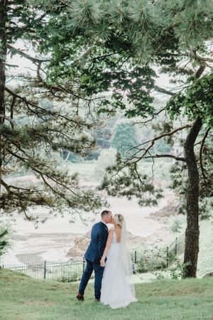 Romantic wedding portrait under towering pine trees with misty background.