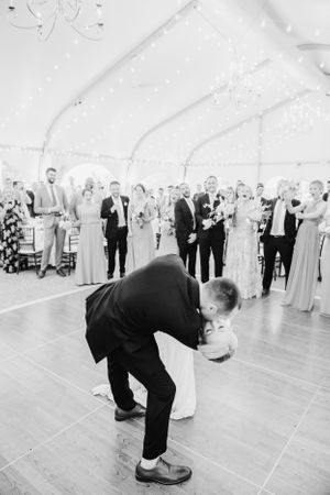 Black and white photo of a romantic wedding dance dip in a tent reception.