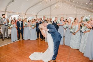Wedding reception in a white tent with light-blue bridesmaid dresses and romantic string lights.