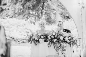 Black and white photo of a wedding ceremony with lush floral arrangements.