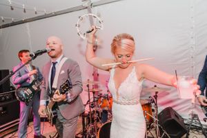 Wedding band performing live music while bride dances at reception.