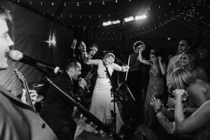 Black and white photo of wedding reception dance party with string lights overhead.