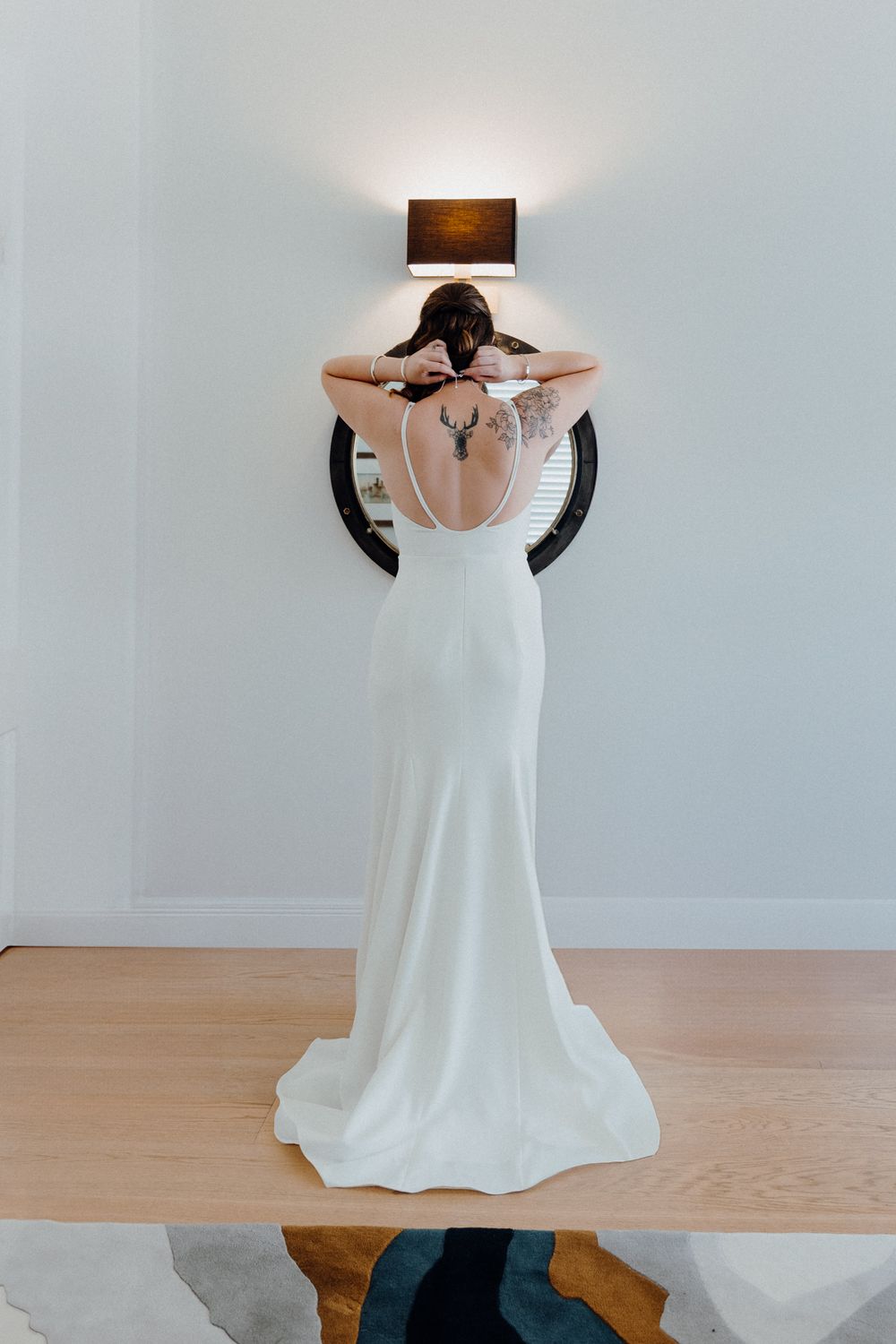Bride in a sleek white wedding gown standing against a white wall captured by Apertured Media Auckland Wedding Photographer.
