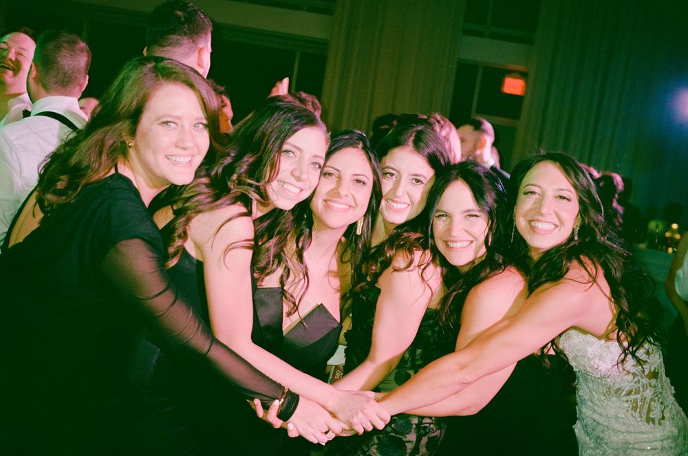A group of people pose together at a party in a dimly lit venue with green lighting.