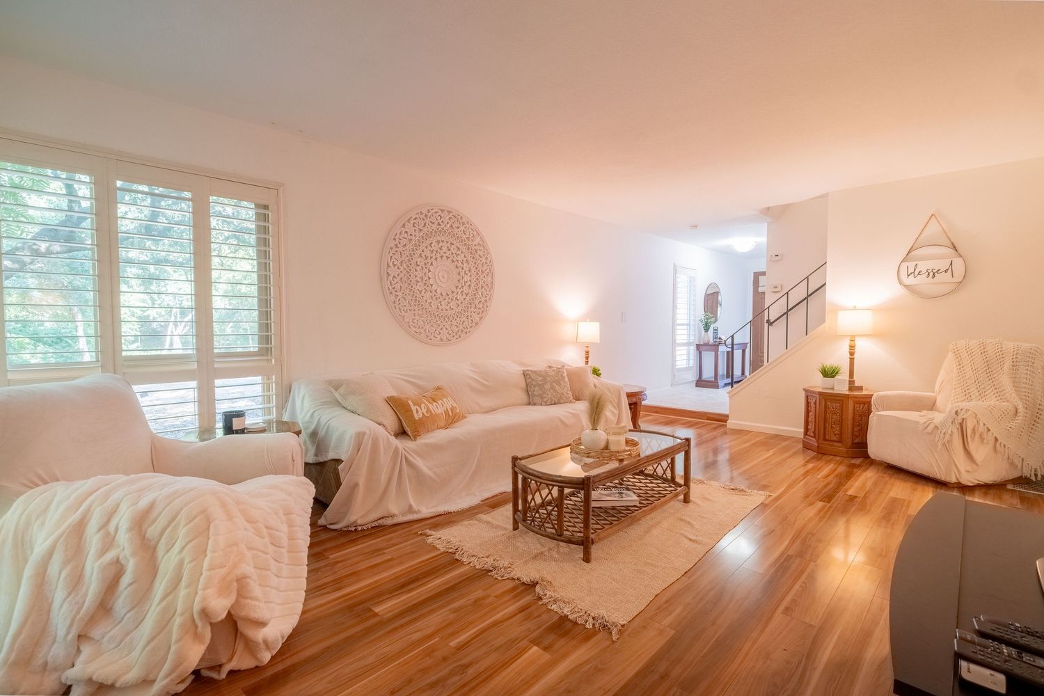 Bright white interior of a cozy bedroom with iron bed frame and warm natural lighting through windows.