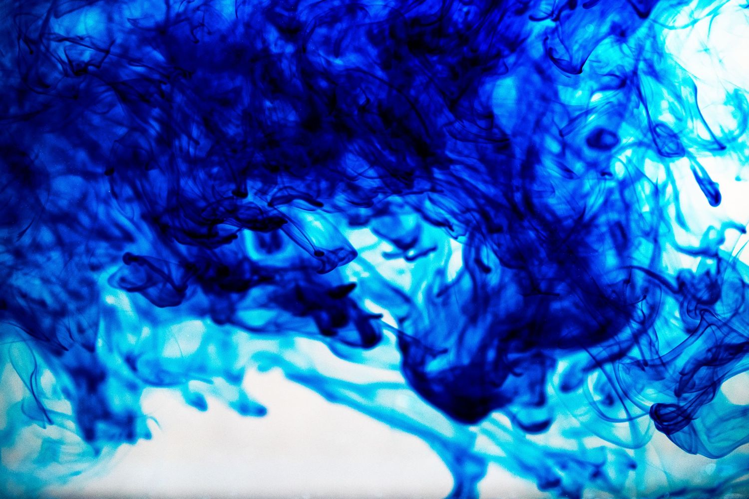 Abstract background of swirling blue ink in water creating ethereal patterns.