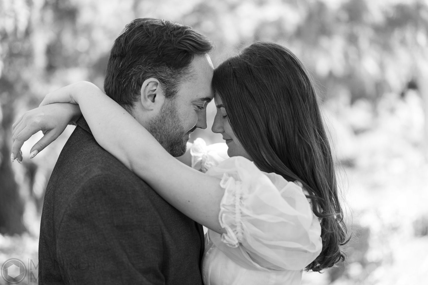 Intimate black and white portrait of a couple sharing a romantic moment outdoors.