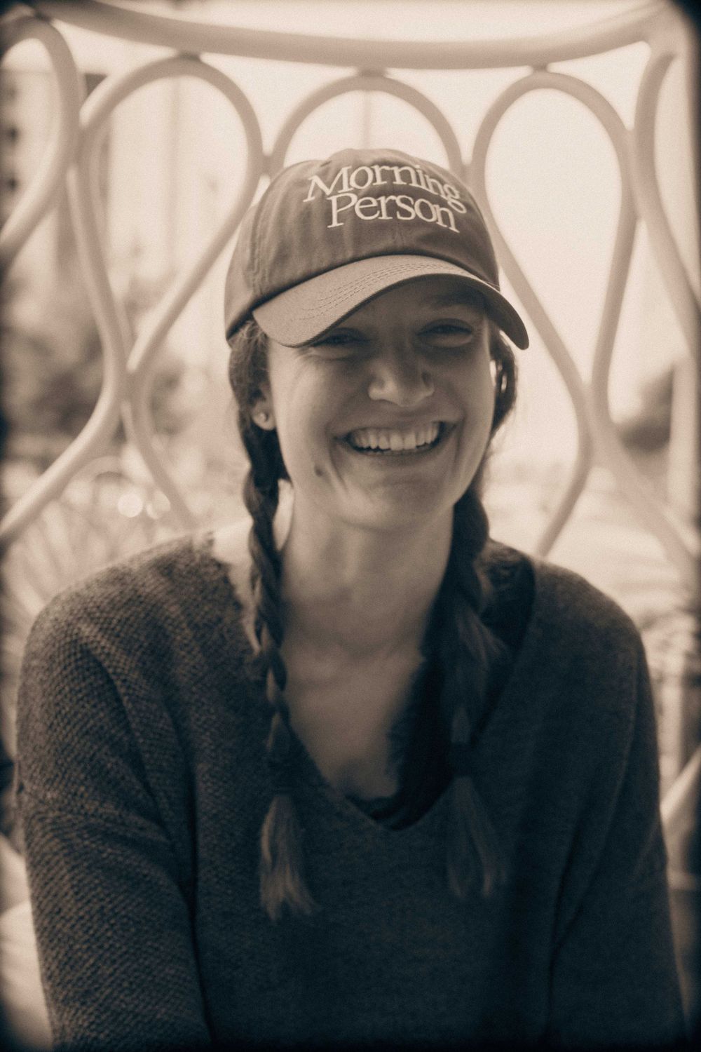 Sepia toned portrait showing person in Morning Person cap with braided hair.