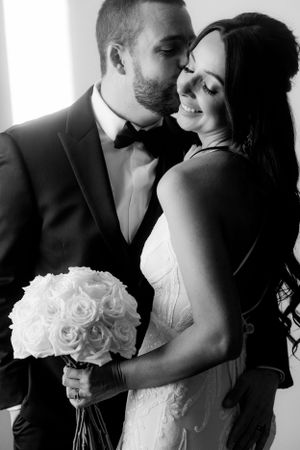 Romantic black and white portrait of newlyweds with white rose bouquet.