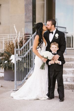 Wedding portrait of a couple and young ring bearer standing on stone steps with autumn decor.