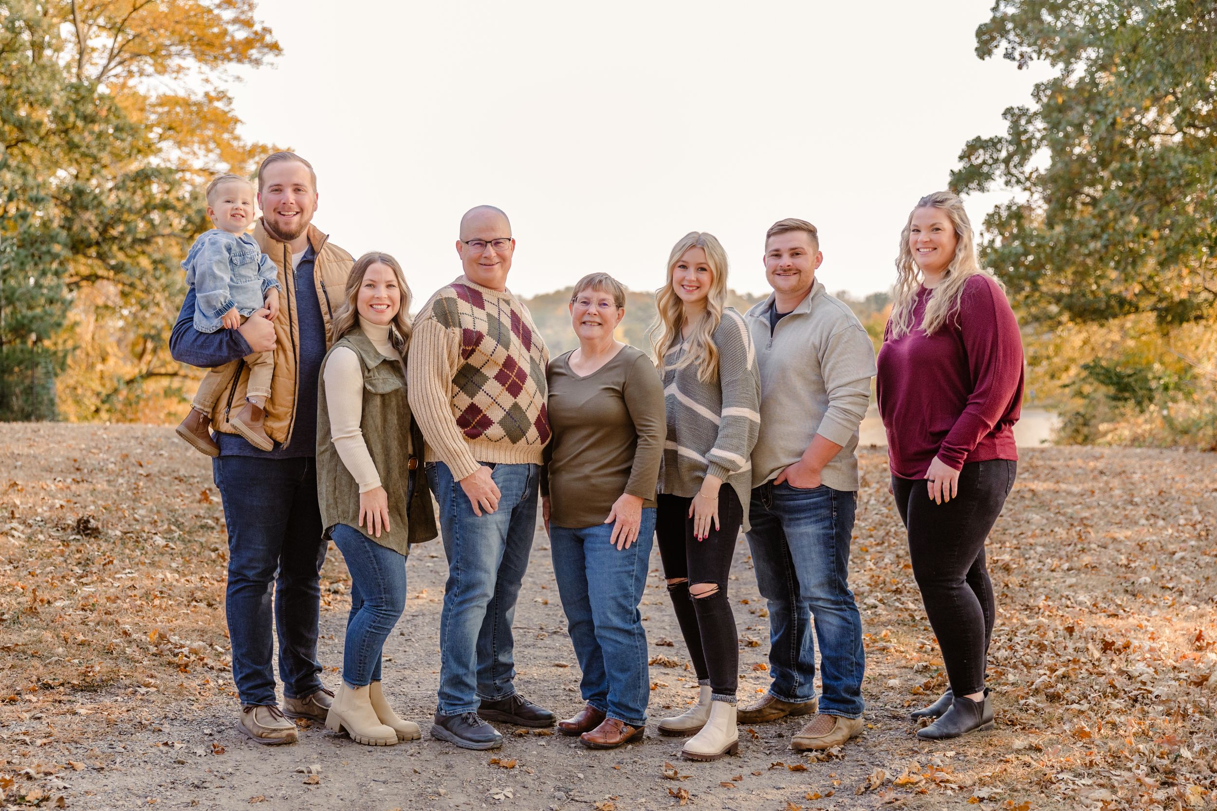 Large family group sitting together for casual outdoor autumn portrait.