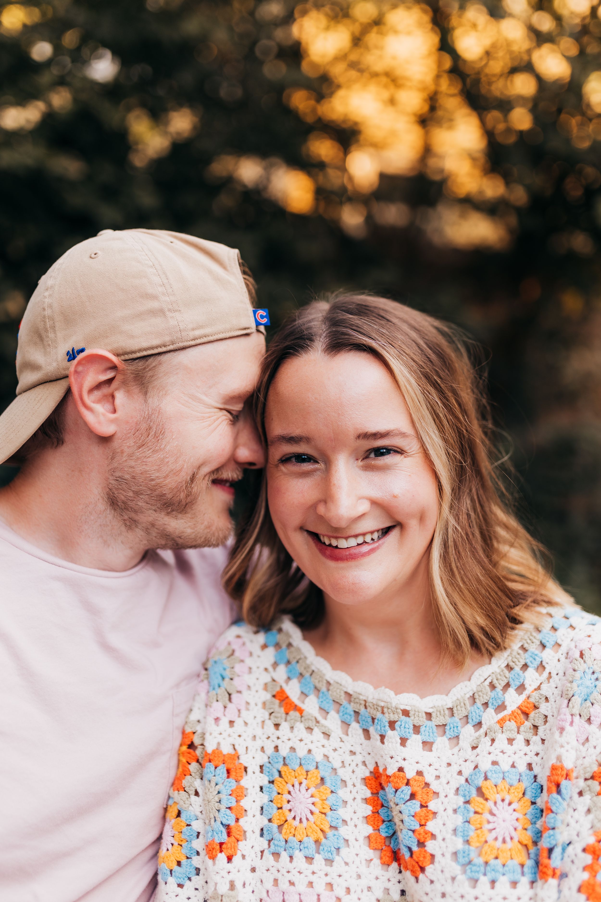 A couple shares an intimate moment during golden hour with warm bokeh lighting.