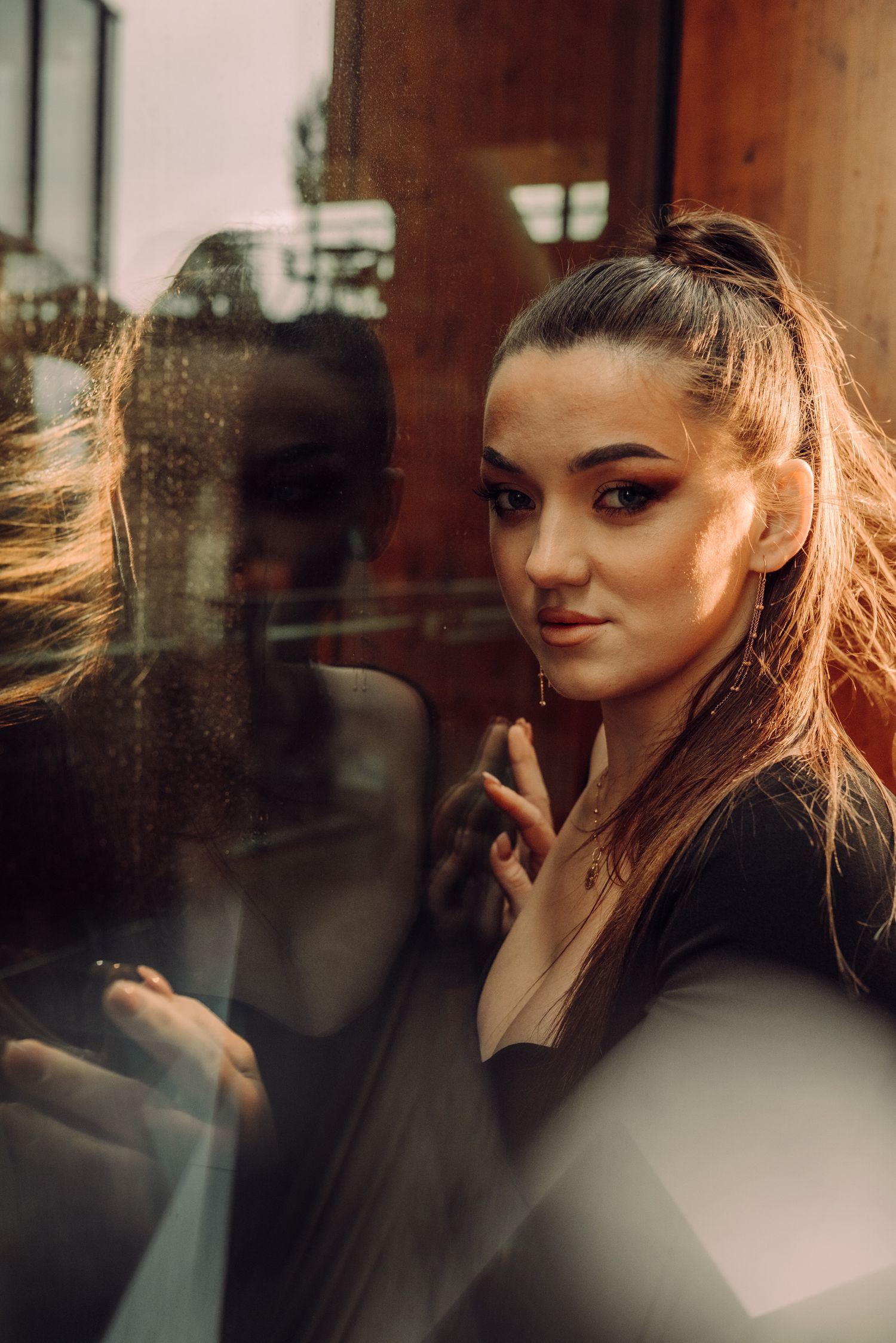 Analog-style individual portrait of a woman with her reflection in a glass window during a solo photoshoot in Amsterdam.