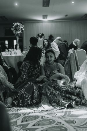 Wedding reception guests in formal attire sitting at decorated tables with ornate carpeting.