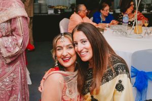 Guests in traditional formal attire share a joyful moment at a celebration event.