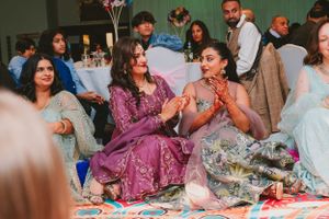 Attendees in elegant formal wear sitting on floor cushions during cultural celebration.