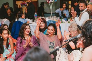 Guests celebrating at a wedding reception with joyful expressions and raised hands.