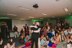 Celebratory dance performance at indoor event with crowd seated on floor cushions watching.