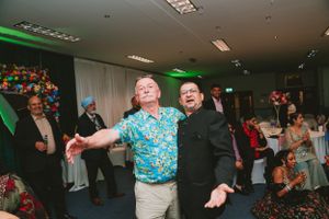 Energetic dance performance at indoor celebration with green lighting and audience watching.