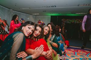 Guests in colorful traditional attire enjoying themselves during indoor celebration.