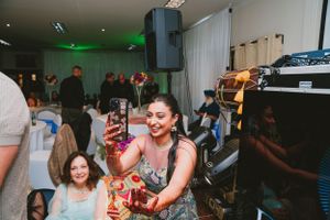 Guests celebrate at an indoor party with festive mood lighting and DJ equipment.