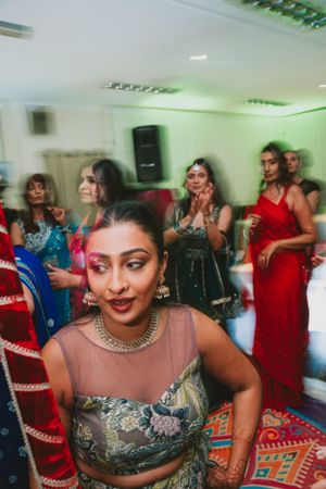 Guests in colorful formal attire dancing at an indoor celebration with green accent lighting.